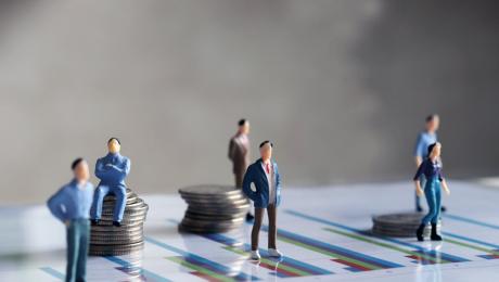 Miniature people standing on charts