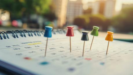 Calendar with multi-colored pushpins on some dates.