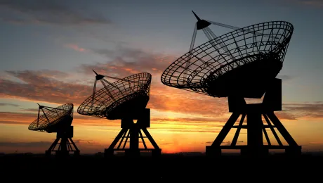 Three large radar receivers with sunset background