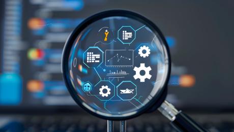 Magnifying glass with computing icons representing software quality & testing
